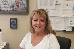 A woman sitting in front of a wall with pictures on it.